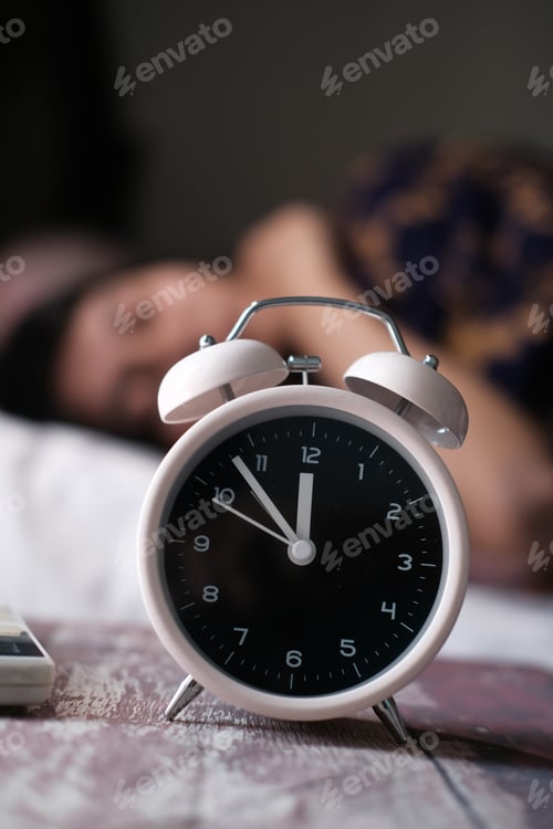 Preview: Alarm clock on table with woman sleeping on background