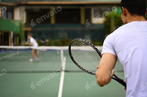 Preview: Back view of tennis player standing in ready position to receive a serve, practicing for competition
