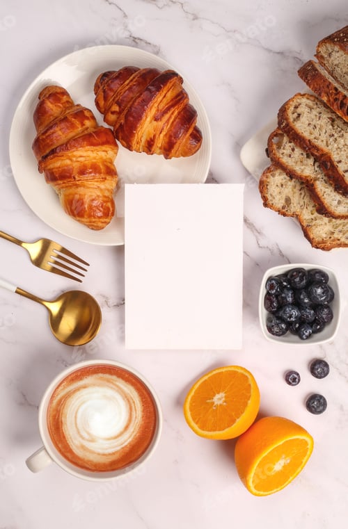 Preview: Top view of croissants with blueberries,oranges and cappuccino served on white table,with copyspace