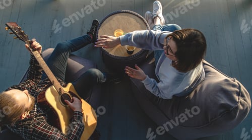 Preview: A young man plays the guitar for a girl, top view.