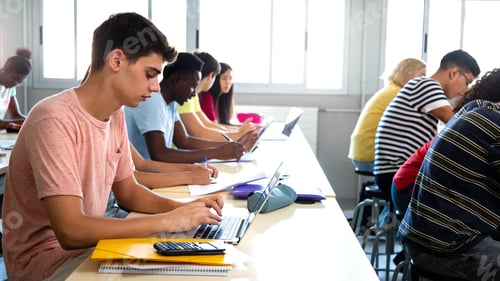 Preview: Side view of group of multiracial high school students studying and using laptops in class.