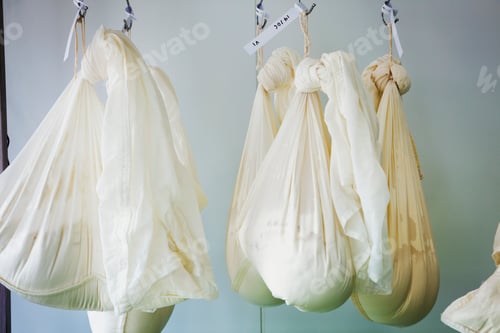 Preview: Gauze bags with goats cheese hanging in a creamery.