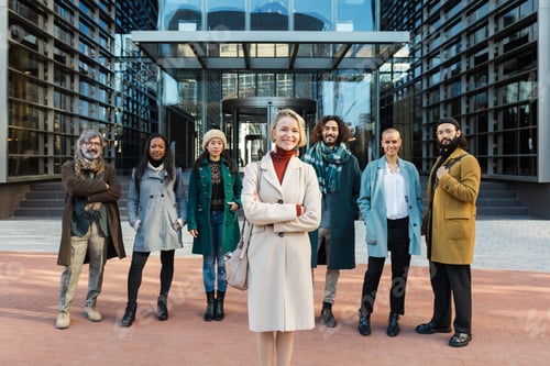 Preview: Merry businesswoman near diverse colleagues on street
