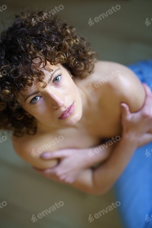Preview: Serious naked woman with arms on chest looking at camera