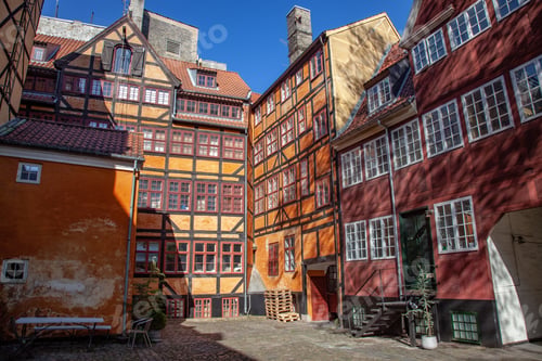 Preview: low angle view of beautiful historical houses against blue sky and cozy empty yard in copenhagen,