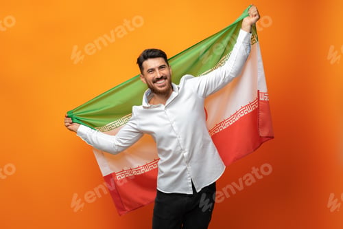 Preview: Portrait of a young casual man holding flag of Iran against orange background