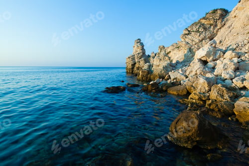 Preview: Seascape of still blue sea waters and rocky coastline