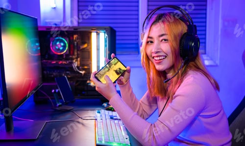 Preview: Gamer playing online game application on mobile phone wear gaming headphones
