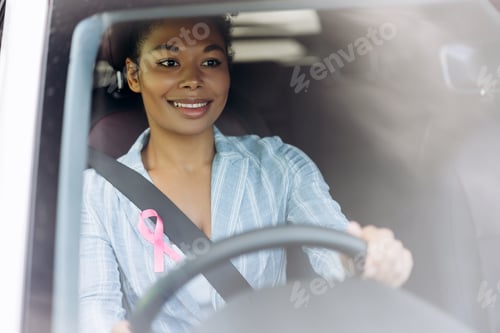Preview: Smiling African American woman with pink ribbon for breast cancer awareness in her car