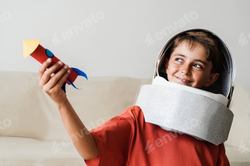 Preview: Astronaut kid playing with helmet toy and crafty rocke Children, space travel concept