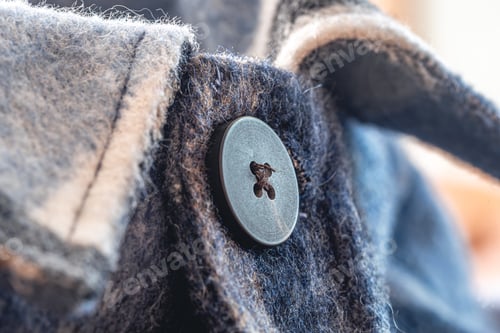 Preview: Button on a warm blue shirt, macro shot.