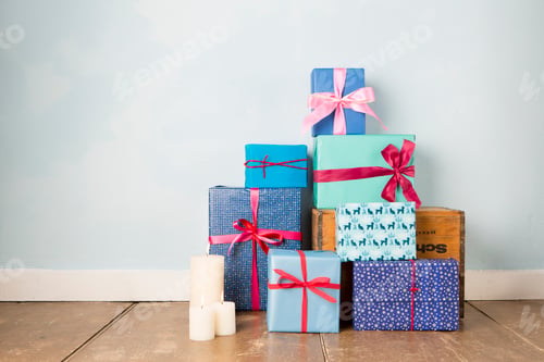 Preview: Candles and stack of wrapped christmas gifts on wooden floor