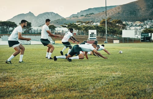 Preview: Full length shot of a group of young rugby players training with bands on the field during the day