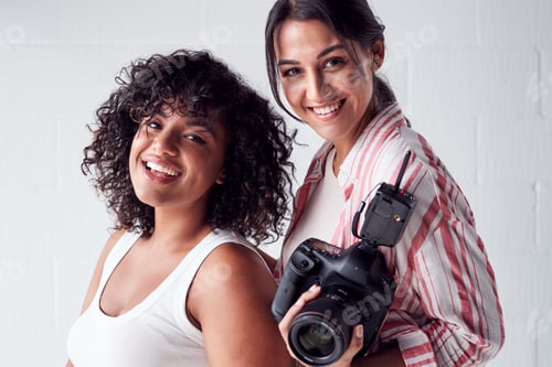 Preview: Portrait Of Smiling Female Photographer Holding Camera With Model In Studio Portrait Session