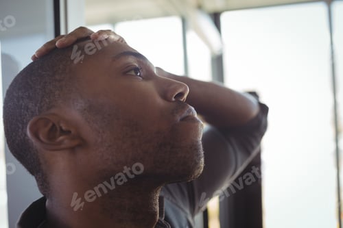 Preview: Worried businessman leaning on glass in office