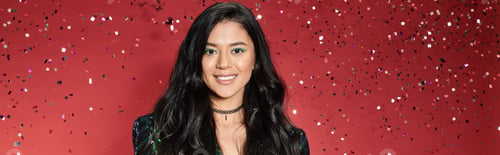 Preview: joyful asian woman in green jacket with sequins standing under falling confetti on red, banner