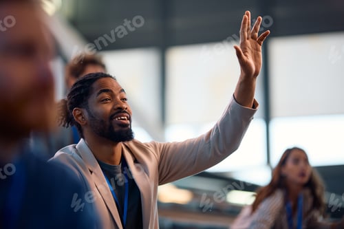 Preview: Black businessman raising his arm to ask a question during a seminar in conference hall.