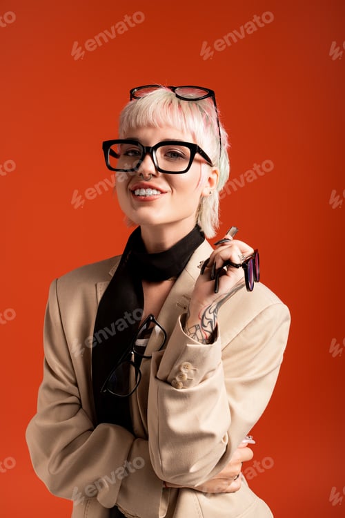 Preview: Young beautiful woman in stylish outfit smiling against vibrant orange background