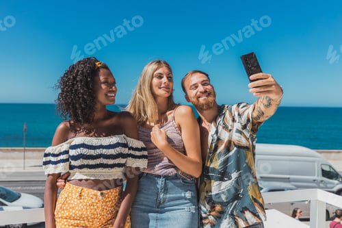 Preview: Diverse friends taking selfie near sea