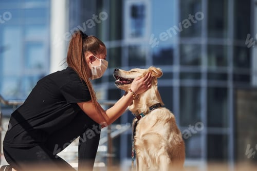 Preview: Young woman in protective mask have a walk outdoors near business building at quarantine time