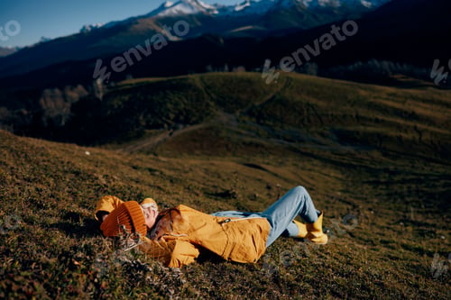 Preview: Woman beautifully lying on a hill recreation smile with teeth in the mountains in the autumn in a