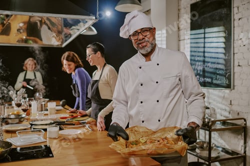 Preview: Middle Aged Man Presenting Freshly Baked Dish during Cooking Class