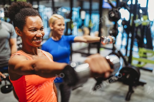 Preview: Group of young happy fit people doing exercises in gym