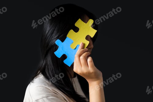 Preview: Girl Covering Face With Puzzle Pieces Against Dark Background