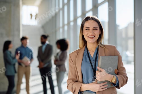 Preview: Happy female entrepreneur in hallway of an office building looking at camera.