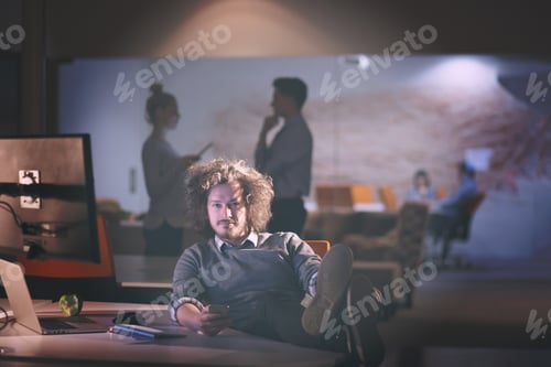 Preview: businessman sitting with legs on desk at office
