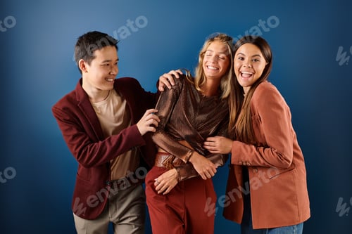 Preview: jolly multiracial teenage friends in fashionable attires having fun together on blue backdrop