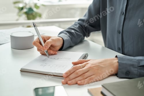 Preview: Manager writing financial strategy in notepad