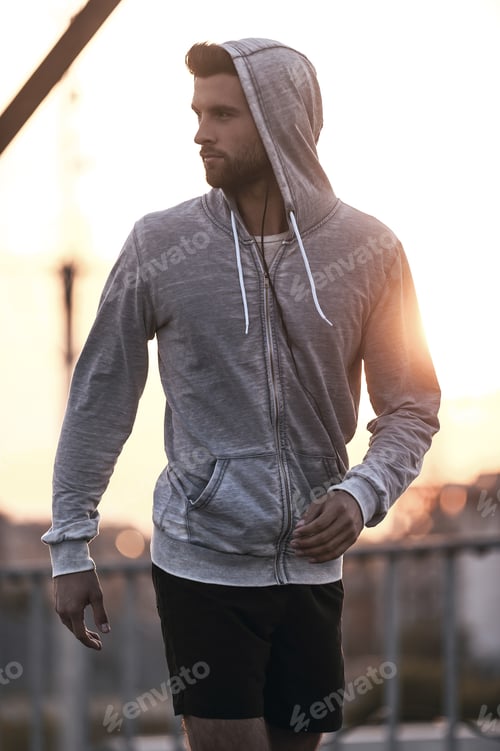 Preview: Sporty handsome. Confident young man in sports clothing looking over shoulder while walking outdoors