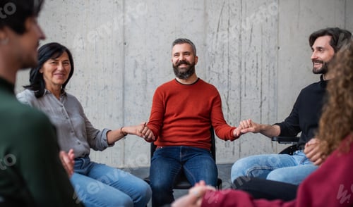 Preview: Men and women sitting in circle during group therapy, holding hands