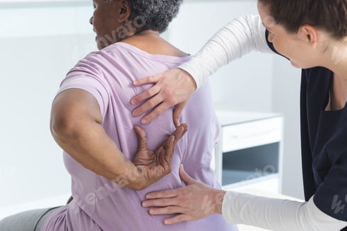 Preview: Diverse female doctor testing back of senior female patient in hospital room
