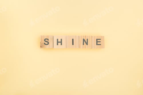 Preview: top view of shine lettering made of wooden cubes on yellow background