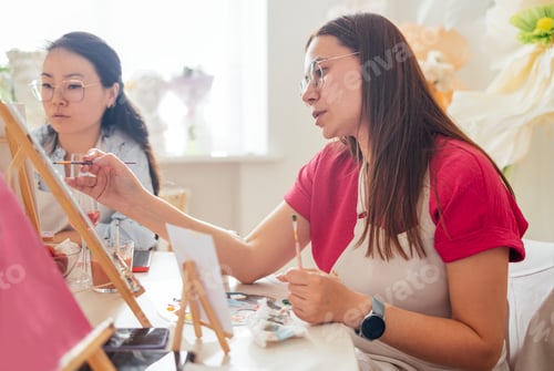 Preview: Close-up of young women in casual clothes at a painting workshop