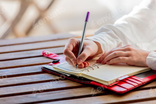 Preview: hand with pen writing something in to a notebook