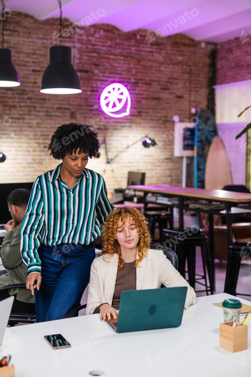 Preview: Multi ethnic team working together on laptop in modern office