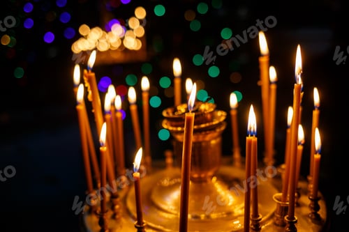 Preview: Many burning candles stand in a golden stand in the church. Selective focus