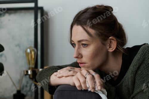 Preview: Young woman experiences feelings of sadness at home while lost in thought