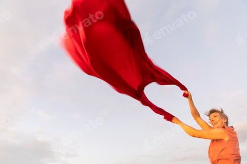 Preview: Woman holding up red cloth fluttering in wind