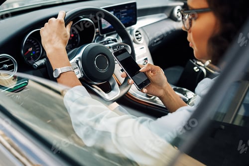 Preview: Unrecognizable woman using smartphone while sitting in car.