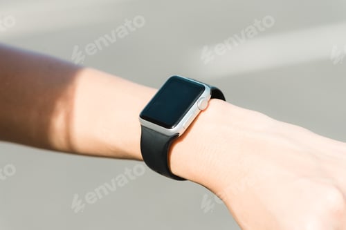 Preview: Close up of a young Asian woman looking on her smartwatch in the green garden.