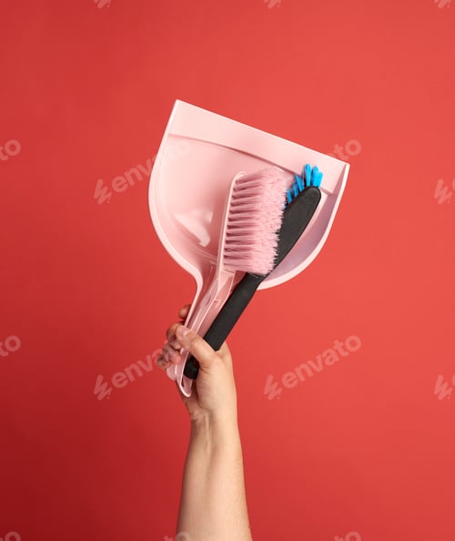 Preview: Female hand holds a plastic scoop and brush on a red background