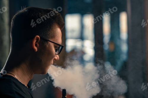 Preview: A man in glasses smokes a traditional hookah pipe A man exhales thick smoke in a hookah cafe