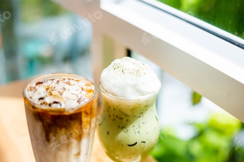 Preview: Two glasses on wooden table. Ice matcha green tea latte with milk and ice coffee