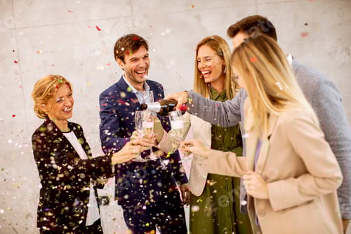 Preview: Group of business people celebrating and toasting with confetti falling in the office