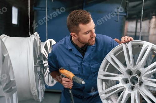 Preview: Ready to adjust the wheel. Car service station worker is taking care about disks of tires