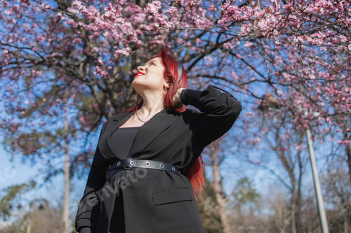 Preview: Woman with cherry flowers surrounded by blossoming trees copy space. Beauty and seasonal change and